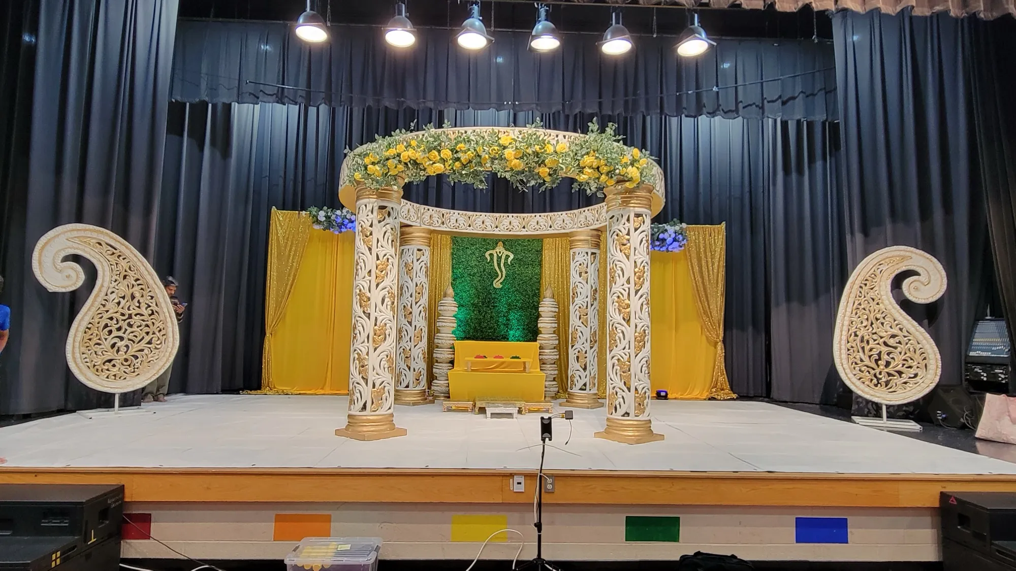 Mandap angle finials greenery wall — Yellow & Gold Mandap with Paisley Pillars